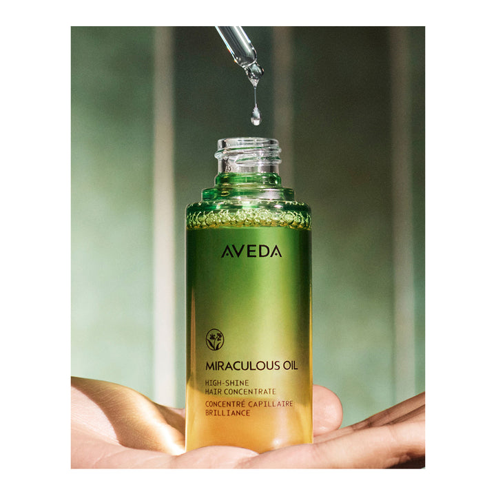 Aveda Miraculous Oil bottle with dropper on a blurred green background