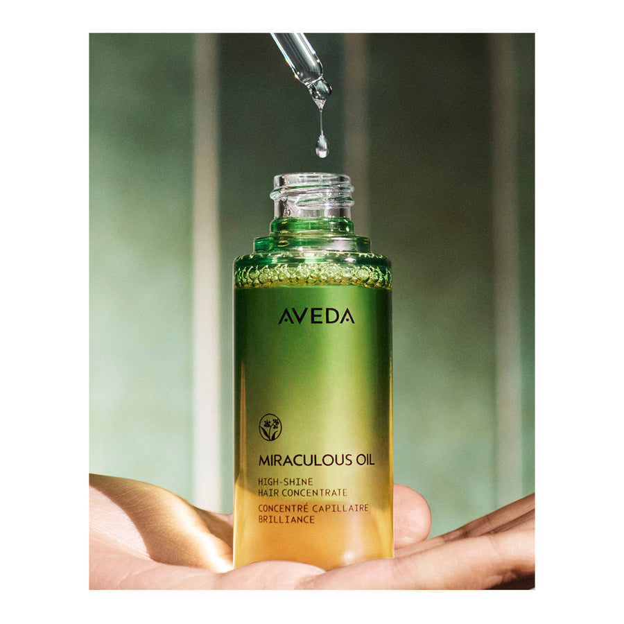 Aveda Miraculous Oil bottle with dropper on a blurred green background